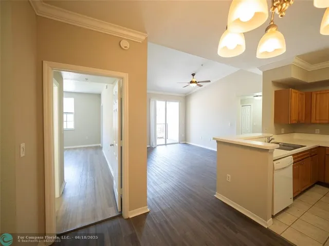 a view of a kitchen with a sink wooden cabinet and stainless steel appliances