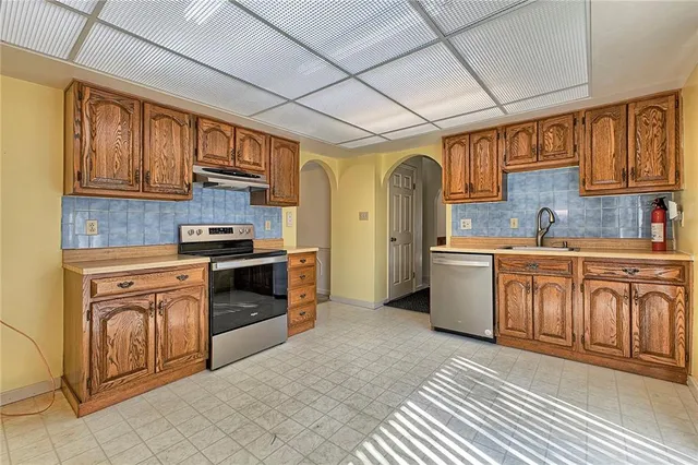 a kitchen with stainless steel appliances granite countertop a refrigerator a sink dishwasher a stove with wooden cabinets and floor