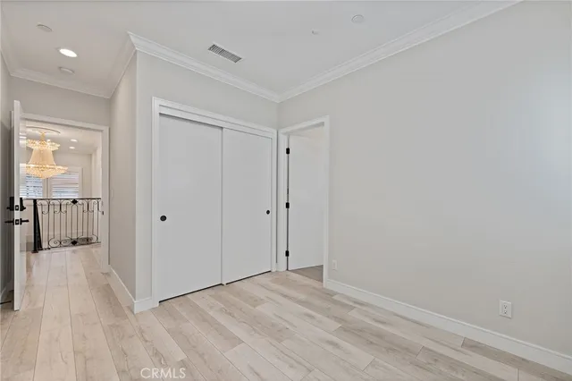a view of a hallway with wooden floor and a bathroom