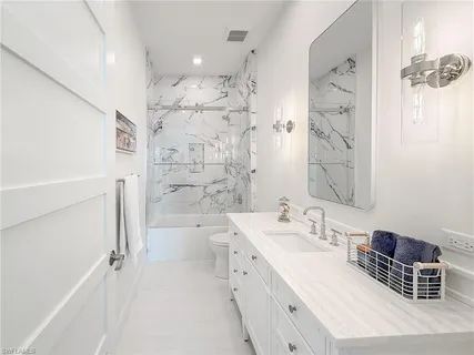 a bathroom with a double vanity sink a toilet a mirror and shower