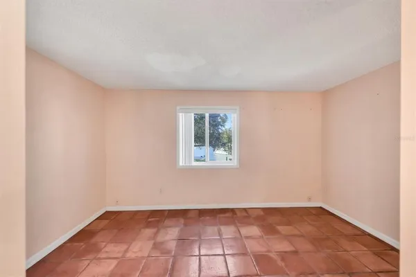 a view of an empty room with window and chandelier fan