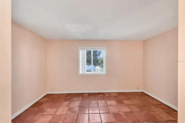 a view of an empty room with window and chandelier fan