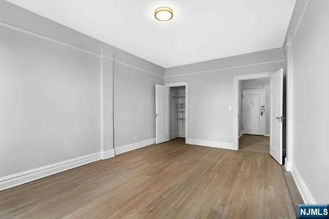 a view of an empty room with wooden floor and closet