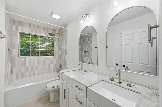 a spacious bathroom with double vanity a toilet a a mirror a bathtub and shower