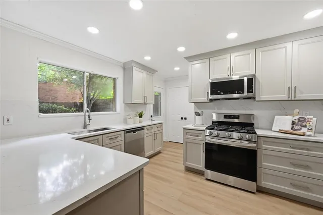 a kitchen with stainless steel appliances granite countertop a stove a sink and a microwave