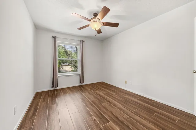 an empty room with windows and ceiling fan