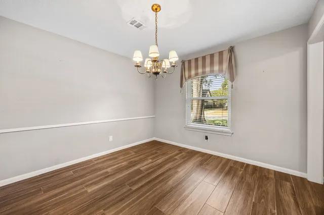a view of a room with wooden floor chandelier and a window