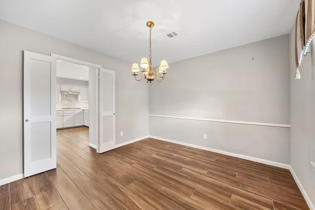 a view of a room with wooden floor and a chandelier