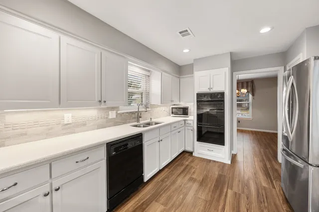 a kitchen with a sink wooden floor and stainless steel appliances