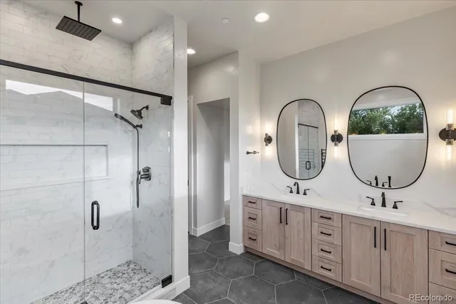 a bathroom with a double vanity sink a two mirror and shower