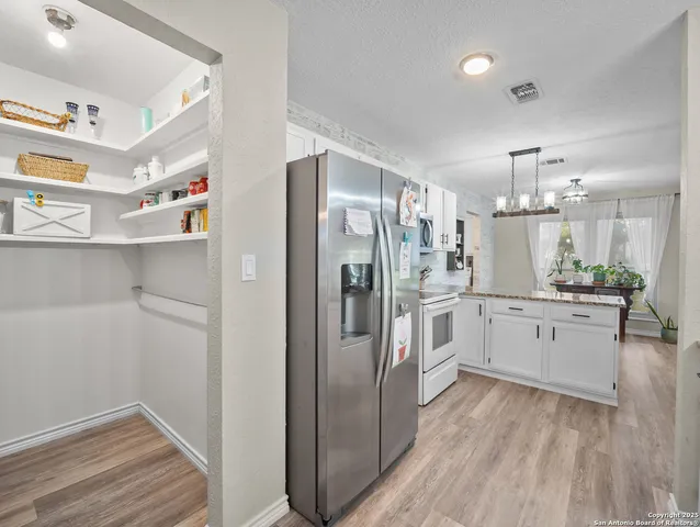 a large kitchen with a refrigerator and countertop cabinets
