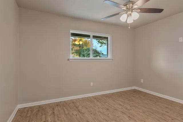 a view of an empty room with wooden floor and a window