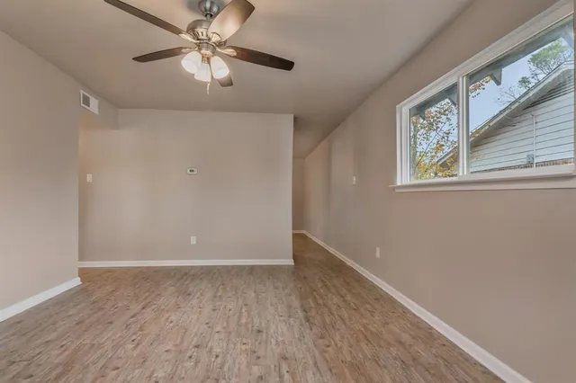 a view of an empty room with window and wooden floor