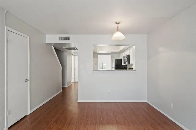 a view of a hallway with wooden floor and a room