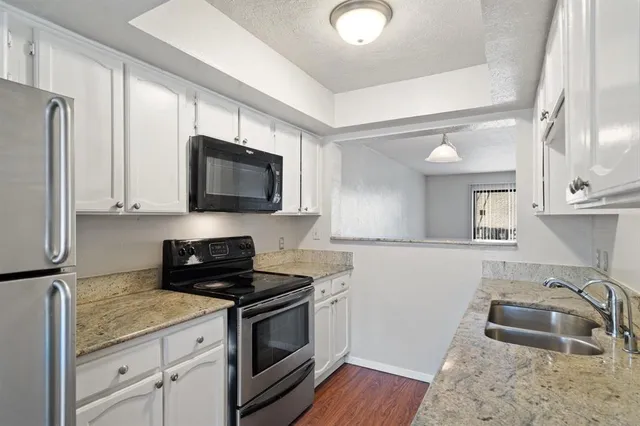 a kitchen with granite countertop a sink stainless steel appliances and cabinets