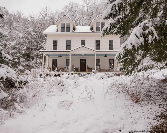 a front view of a house with a yard covered in snow