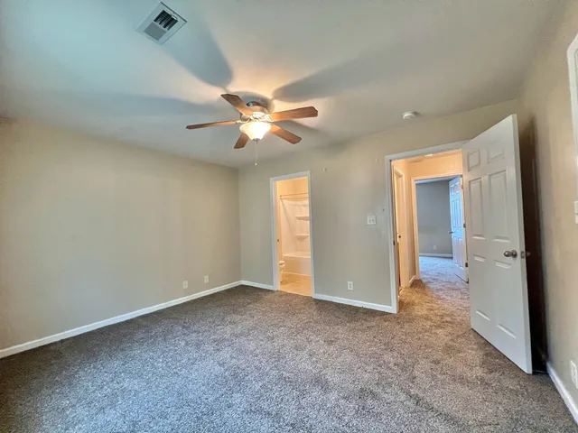 an empty room with closet and a ceiling fan