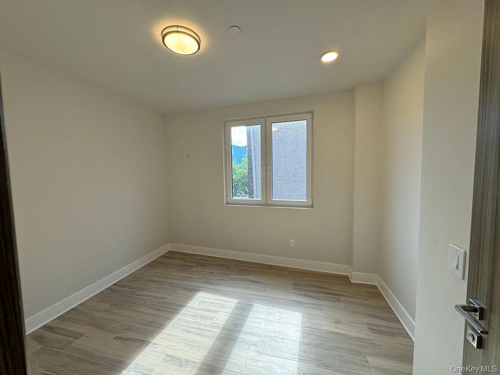 2478 East 11th Street, Unit 2C Brooklyn, NY 11235 - Photo 12 of 16 an empty room with wooden floor and windows