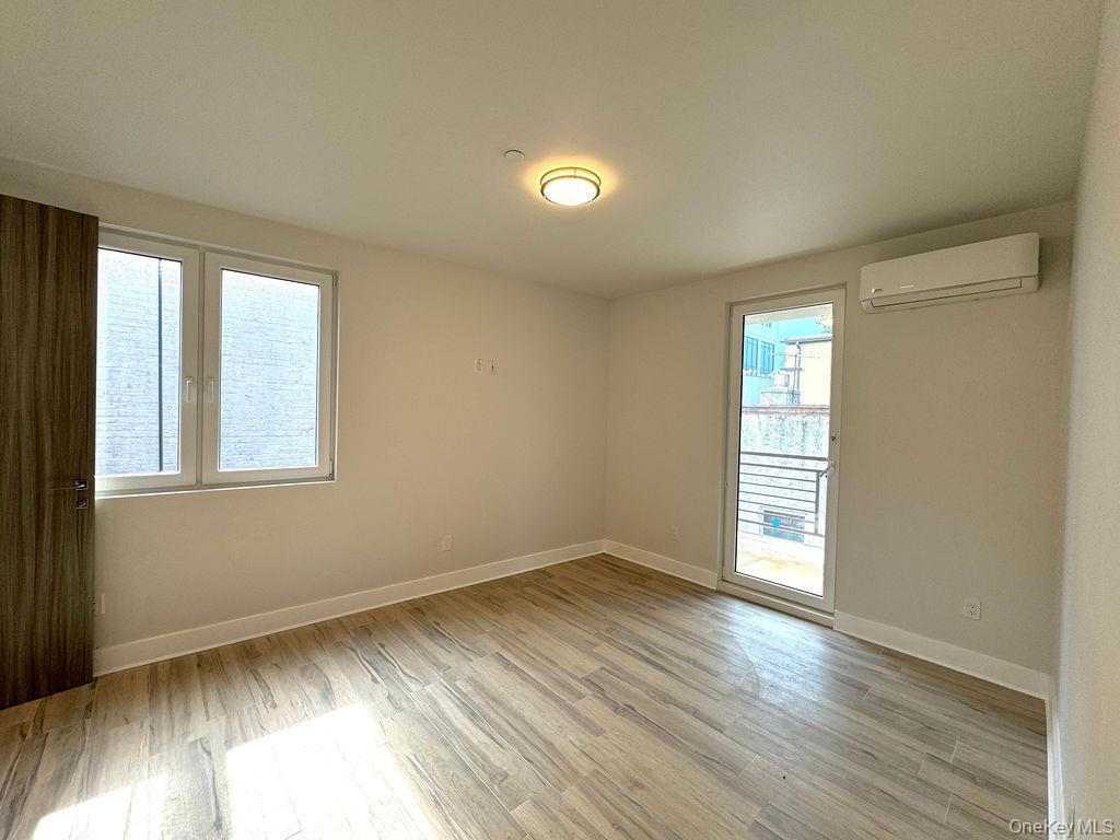 2478 East 11th Street, Unit 2C Brooklyn, NY 11235 - Photo 8 of 16 a view of an empty room with wooden floor and a window