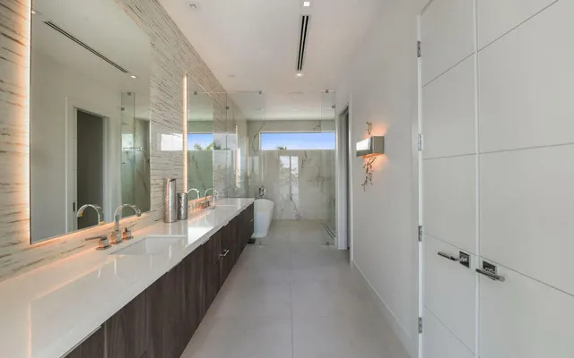 a bathroom with double vanity sinks a large mirror and a shower