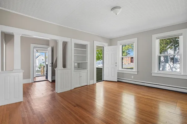 an empty room with wooden floor and windows