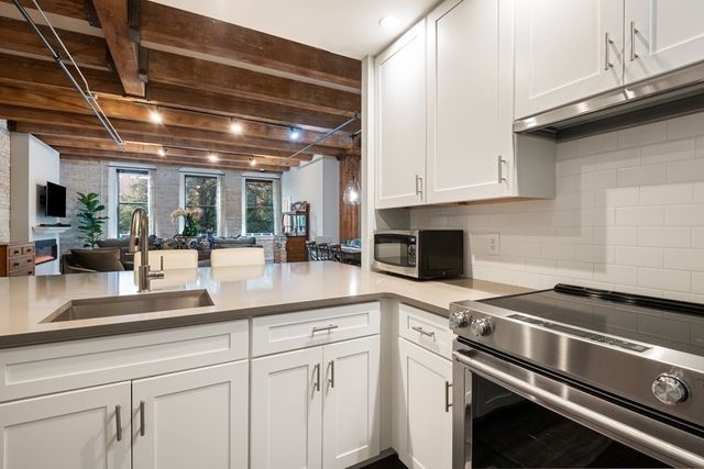 a kitchen with stainless steel appliances granite countertop a sink a stove and white cabinets