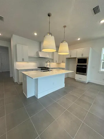 a large kitchen with kitchen island a stove a counter top space a sink and cabinets