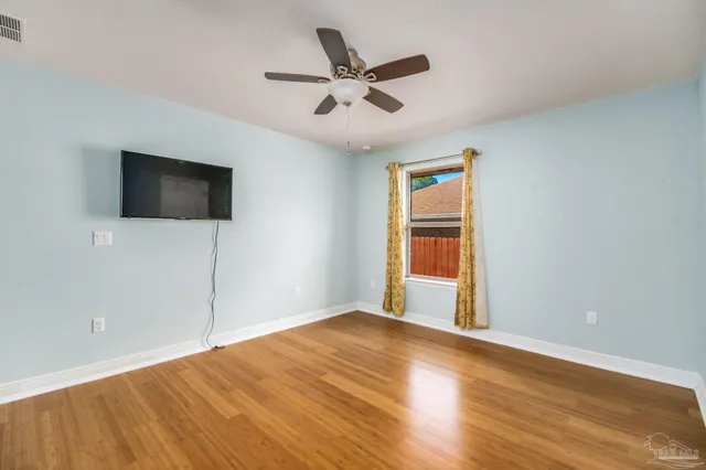 an empty room with wooden floor and ceiling fan