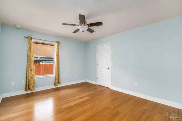 a view of empty room with wooden floor and fan