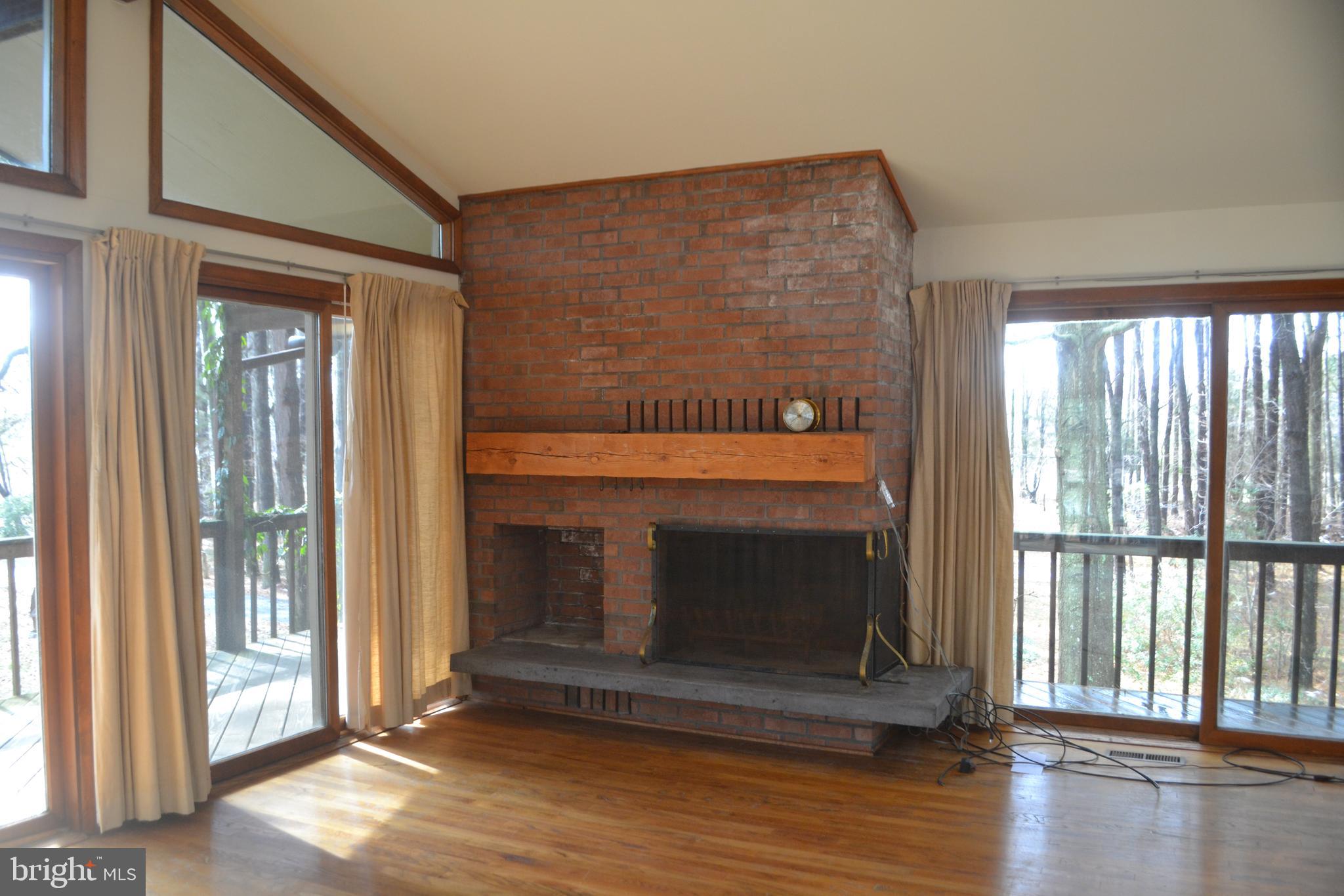 7223 Drum Point Road St. Michaels, MD 21663 - Photo 8 of 38 a living room with a fireplace and floor to ceiling windows