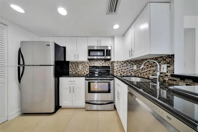 a kitchen with granite countertop white cabinets and stainless steel appliances