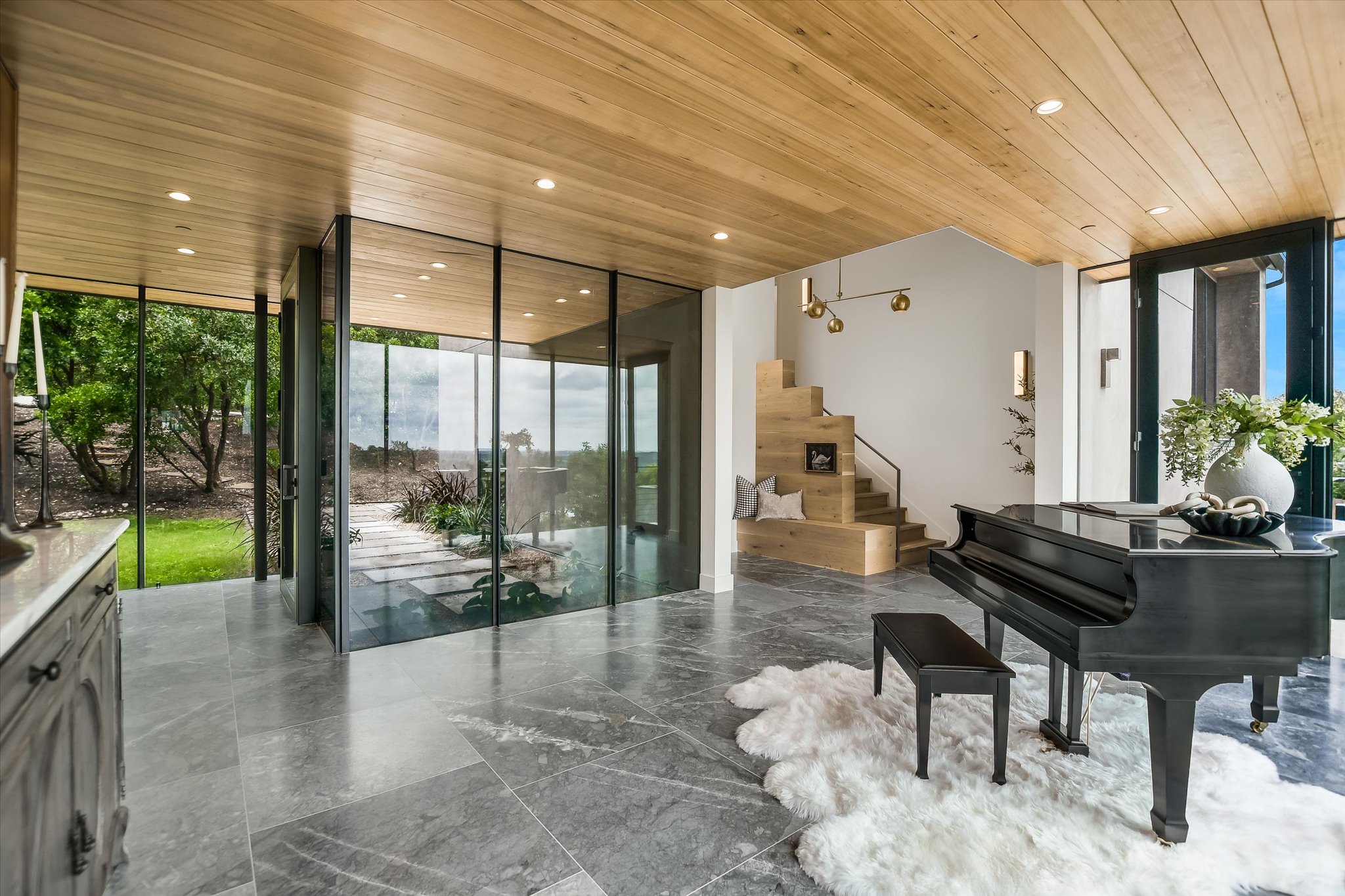 2405 Deer Pass Austin, TX 78746 - Photo 3 of 38 Expansive interior featuring large format stone flooring, a light wood-finish plank ceiling with recessed lighting, and full-height glass panels