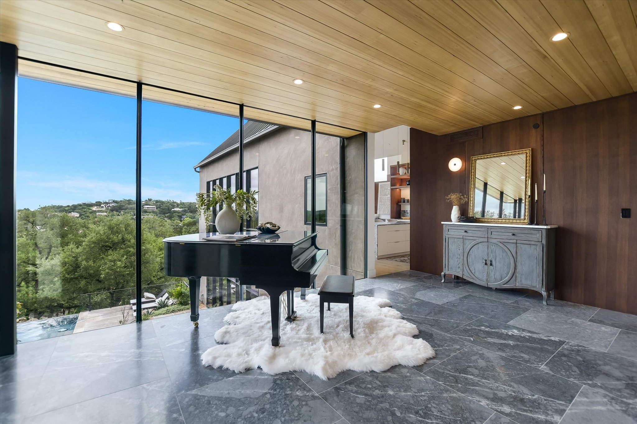 2405 Deer Pass Austin, TX 78746 - Photo 5 of 38 Floor-to-ceiling windows with black framing, wood-panel ceiling, large format stone flooring, wood-paneled accent wall, and recessed lighting