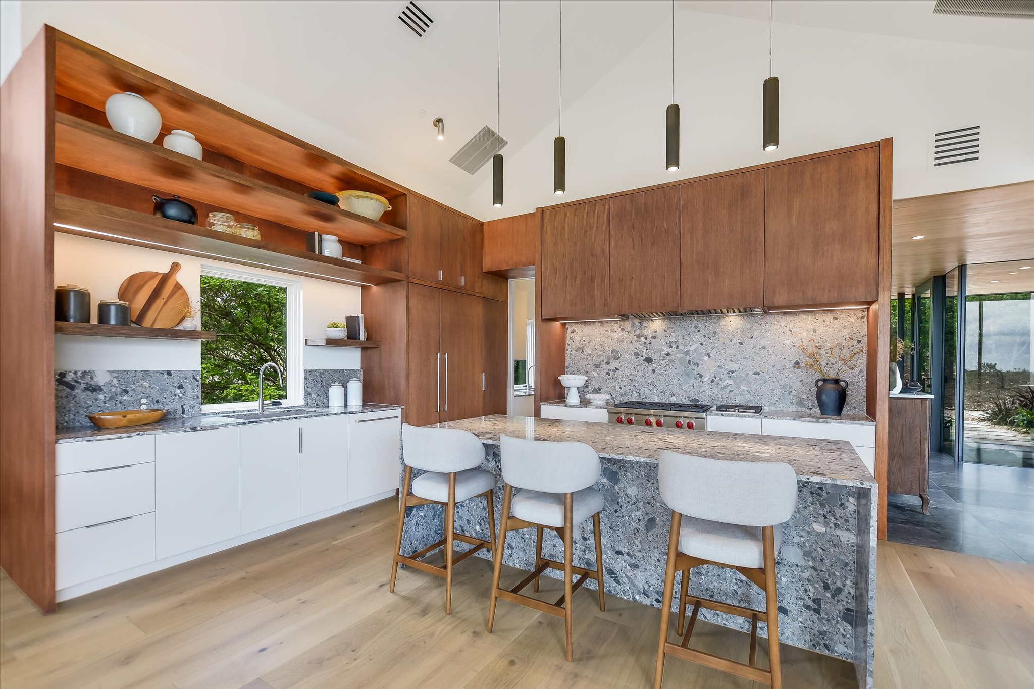2405 Deer Pass Austin, TX 78746 - Photo 7 of 38 Modern kitchen featuring a large waterfall island with integrated seating, a professional-grade range, and a full-height stone backsplash