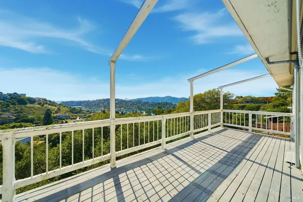 a view of a balcony with wooden floor next to a yard