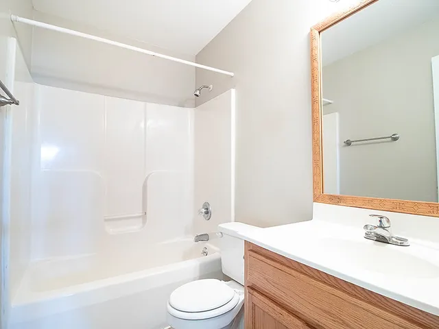 a bathroom with a bathtub shower sink vanity mirror and toilet
