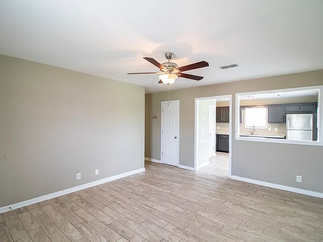 a view of an empty room with window and wooden floor