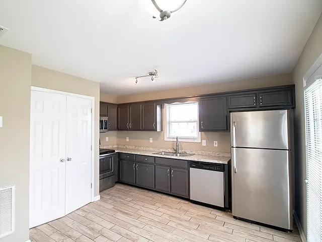 a kitchen with stainless steel appliances granite countertop a refrigerator a sink a stove a microwave and wooden floors