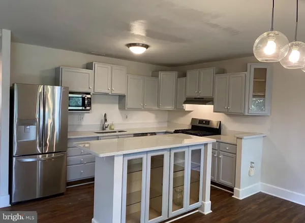 a kitchen with stainless steel appliances granite countertop a refrigerator a stove a sink dishwasher and white cabinets with wooden floor