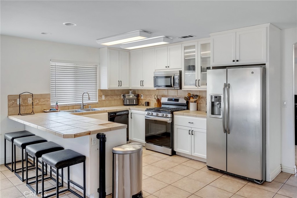 14952 Rivers Edge Road Helendale, CA 92342 - Photo 15 of 33 a kitchen with stainless steel appliances a stove refrigerator sink cabinets dining table and chairs
