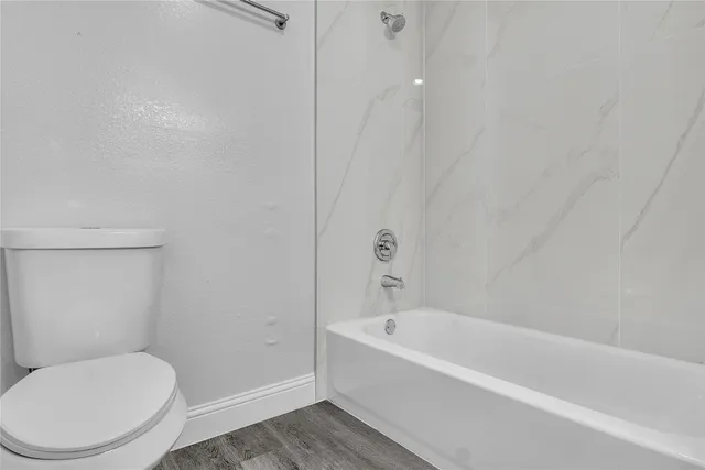 a white toilet sitting next to a bath tub