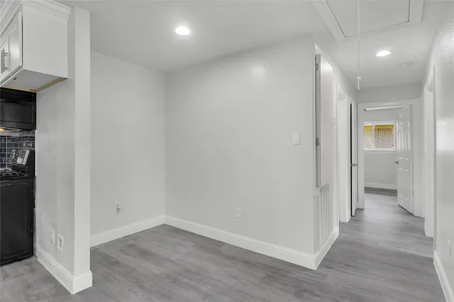 an empty room with wooden floor and a hallway