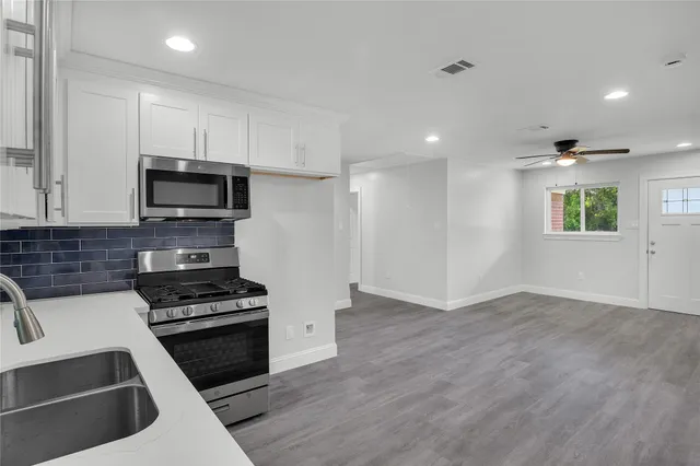 a kitchen with granite countertop a stove a sink and a microwave