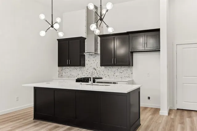 a kitchen with a sink chandelier and wooden floor