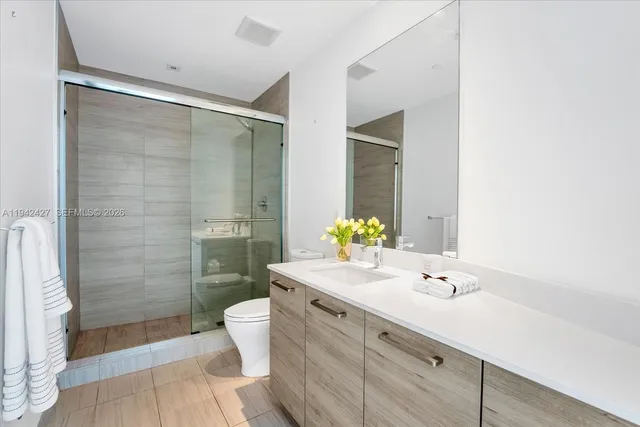 a bathroom with a granite countertop sink a toilet a mirror and shower