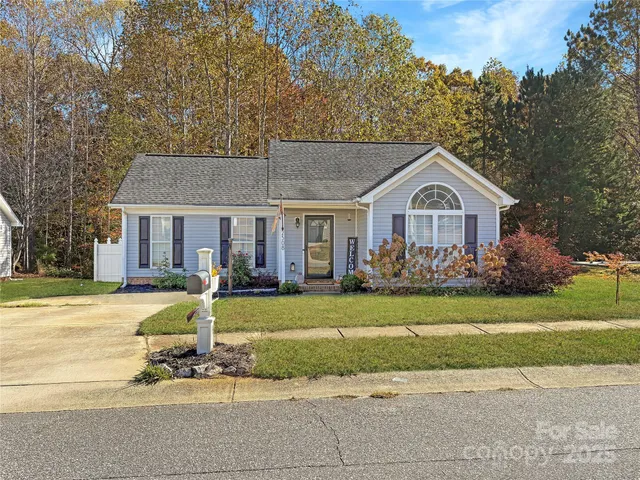 a front view of a house with a yard outdoor seating and covered with trees