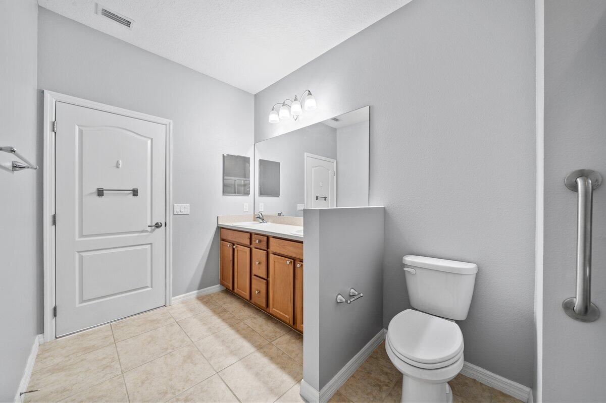 2980 Le Conte Street Melbourne, FL 32940 - Photo 21 of 25 a bathroom with a granite countertop toilet a sink and a mirror