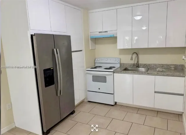 a kitchen with white cabinets and refrigerator