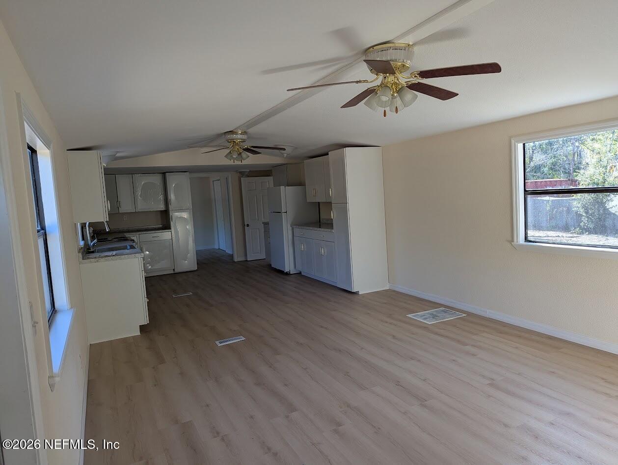 119 Walter Avenue Interlachen, FL 32148 - Photo 11 of 21 a view of a kitchen with a refrigerator a ceiling fan and wooden floor