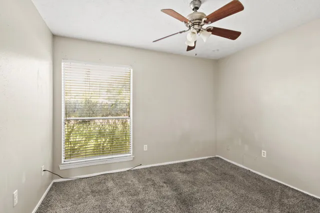 an empty room with windows and fan